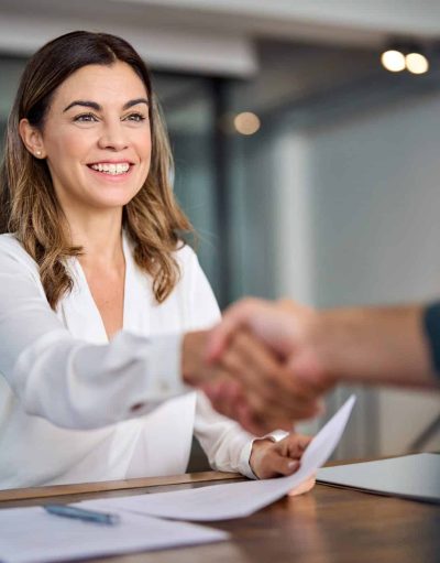 Happy mid aged business woman manager handshaking at office meeting.